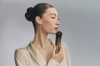 Model in profile holding Bloom 6 to her jawline
