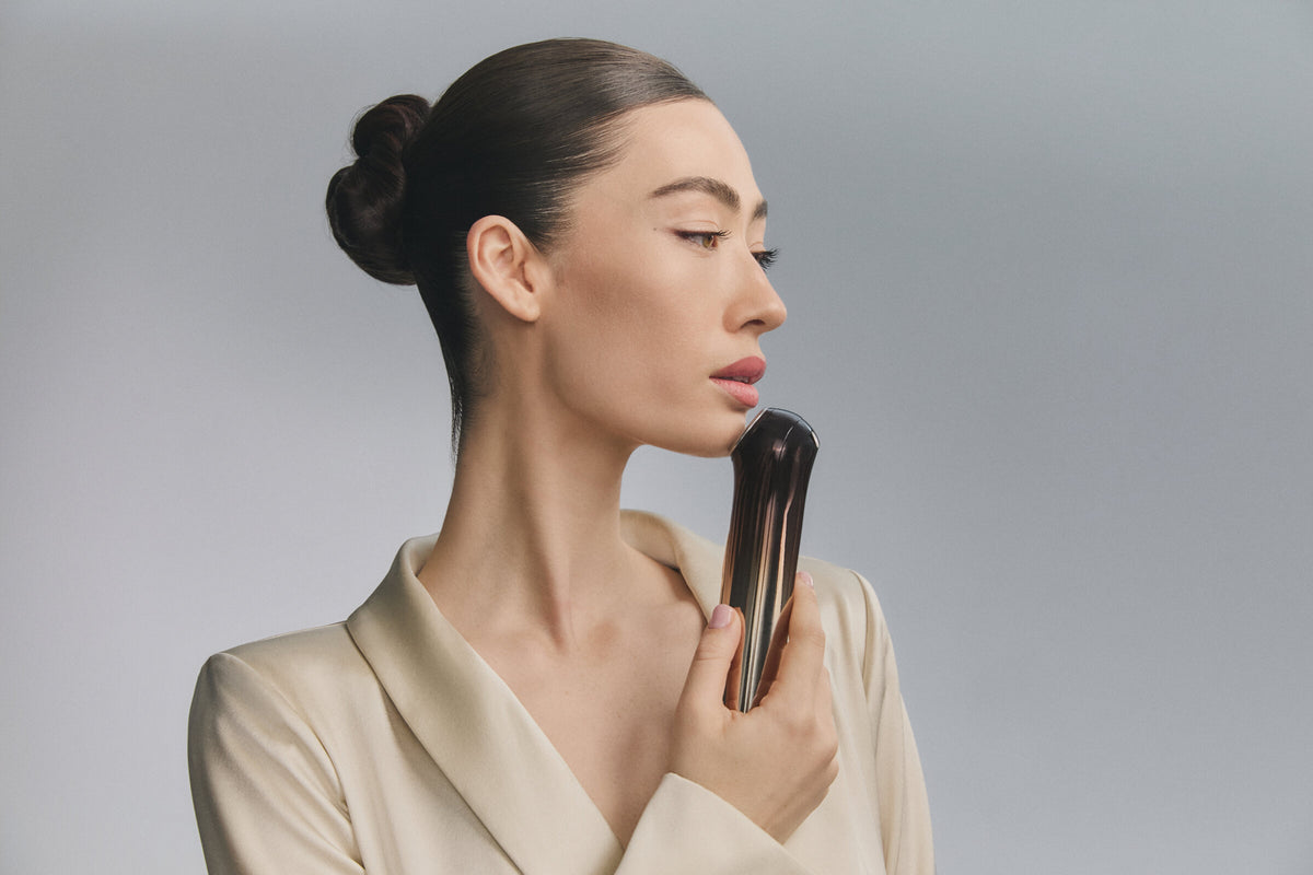 Model in profile holding Bloom 6 to her jawline