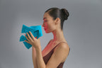 Model in profile holding the Blue Green Mask Lift in teal, red light on