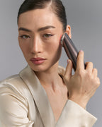 Model holding Photo Plus Deep Lift to her cheek, red light on